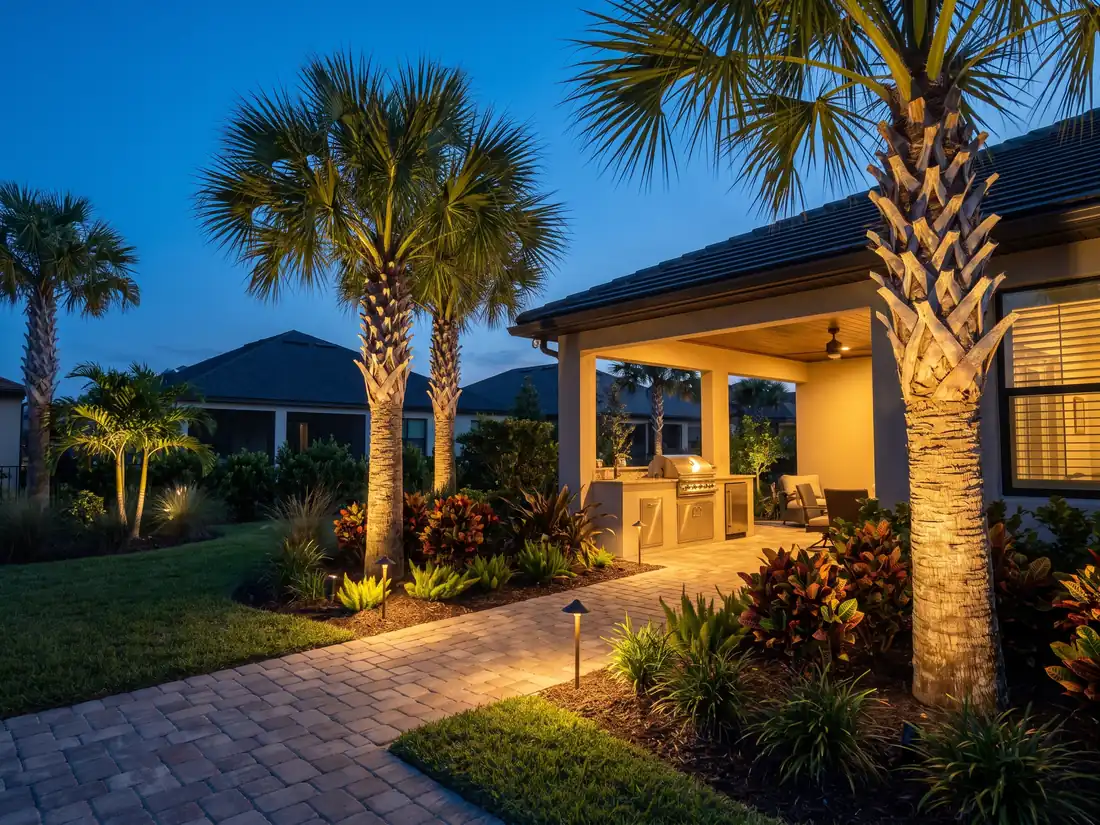 Low-voltage landscape lighting illuminating palms and a paver walkway at dusk